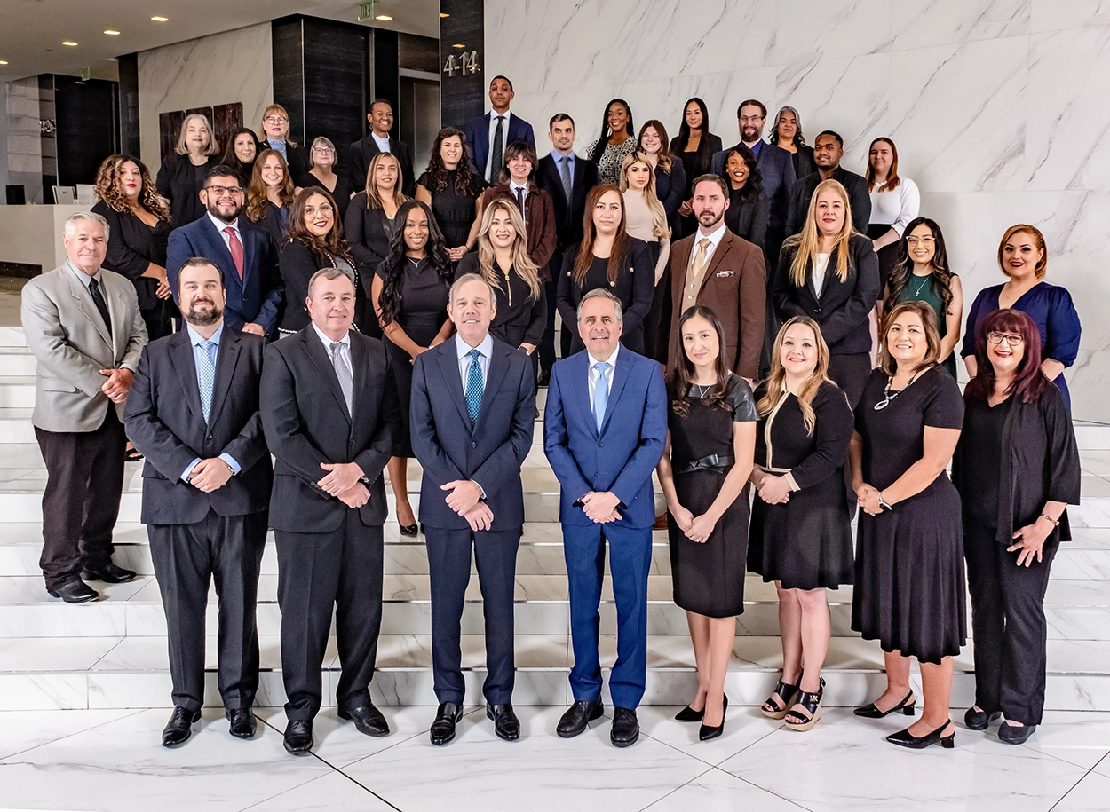 Attorneys and staff of Danziger & De Llano, LLP gathered on a staircase in their office lobby