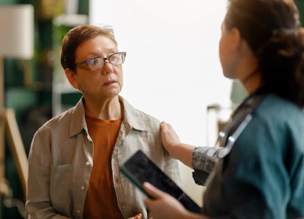 A medical advocate explaining the differences between asbestosis and mesothelioma symptoms to a patient using an informational chart.