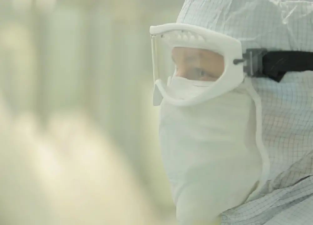 An industrial worker in a protective lab coat and mask, representing workers exposed to contaminated talc in manufacturing settings.