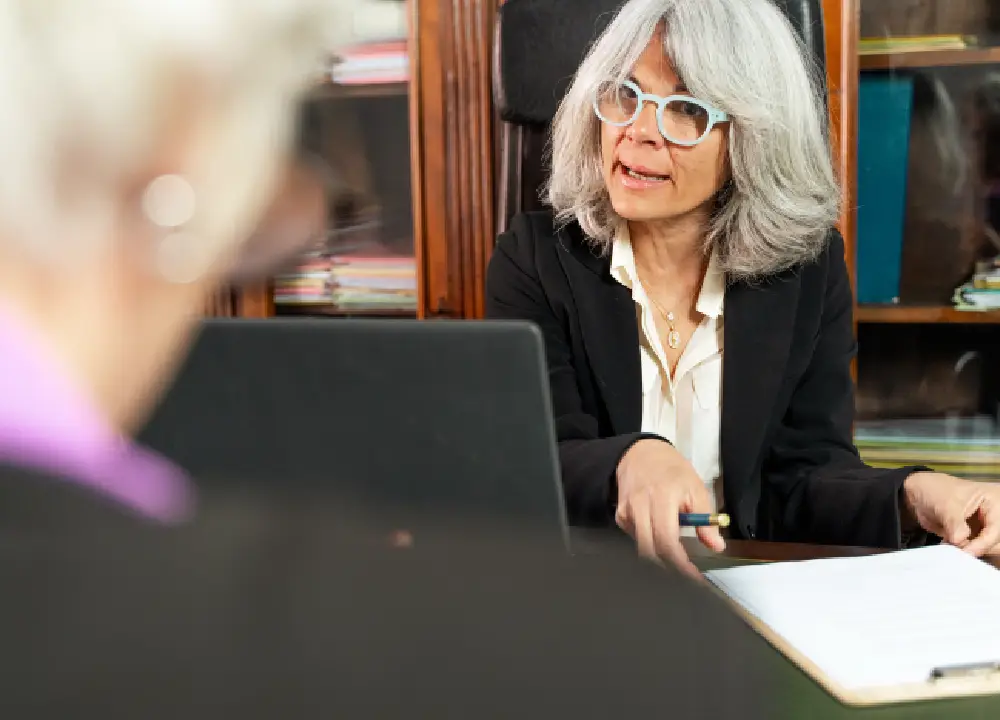 Experienced lawyer consulting with a client and reviewing legal documents in an office.