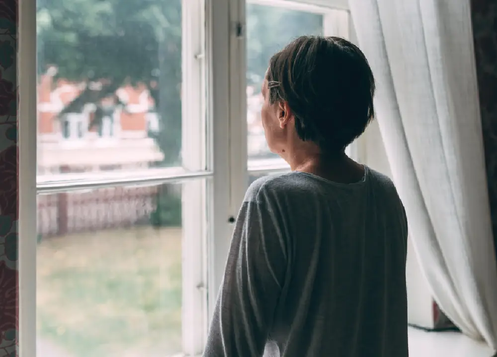 Person looking out a window in a quiet moment of reflection.