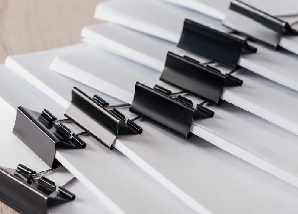 Close-up view of stacks of blank paper secured with metal binder clips.