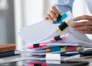 Hands organizing medical records and patient files on a desk to prepare documentation for a mesothelioma claim