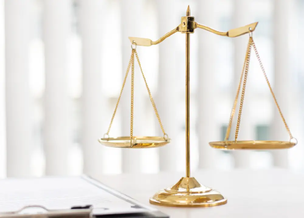 Scales of justice displayed beside legal documents on a desk.