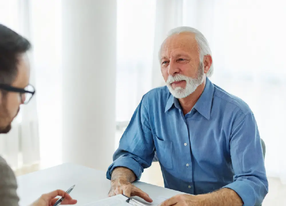 A senior man and a lawyer reviewing medical reports and legal papers together in a professional office.