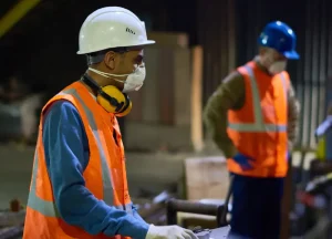 Industrial workers operating machinery inside a metalwork plant, representing potential asbestos exposure in high-risk workplaces